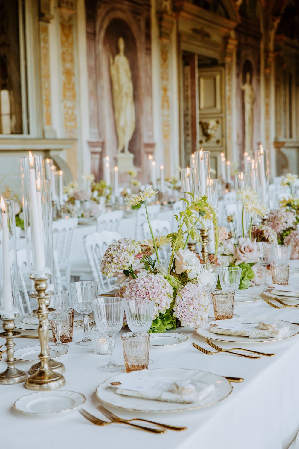 Elegant wedding reception tables set with white linens, crystal candelabras, and delicate floral centerpieces in a grand ballroom.