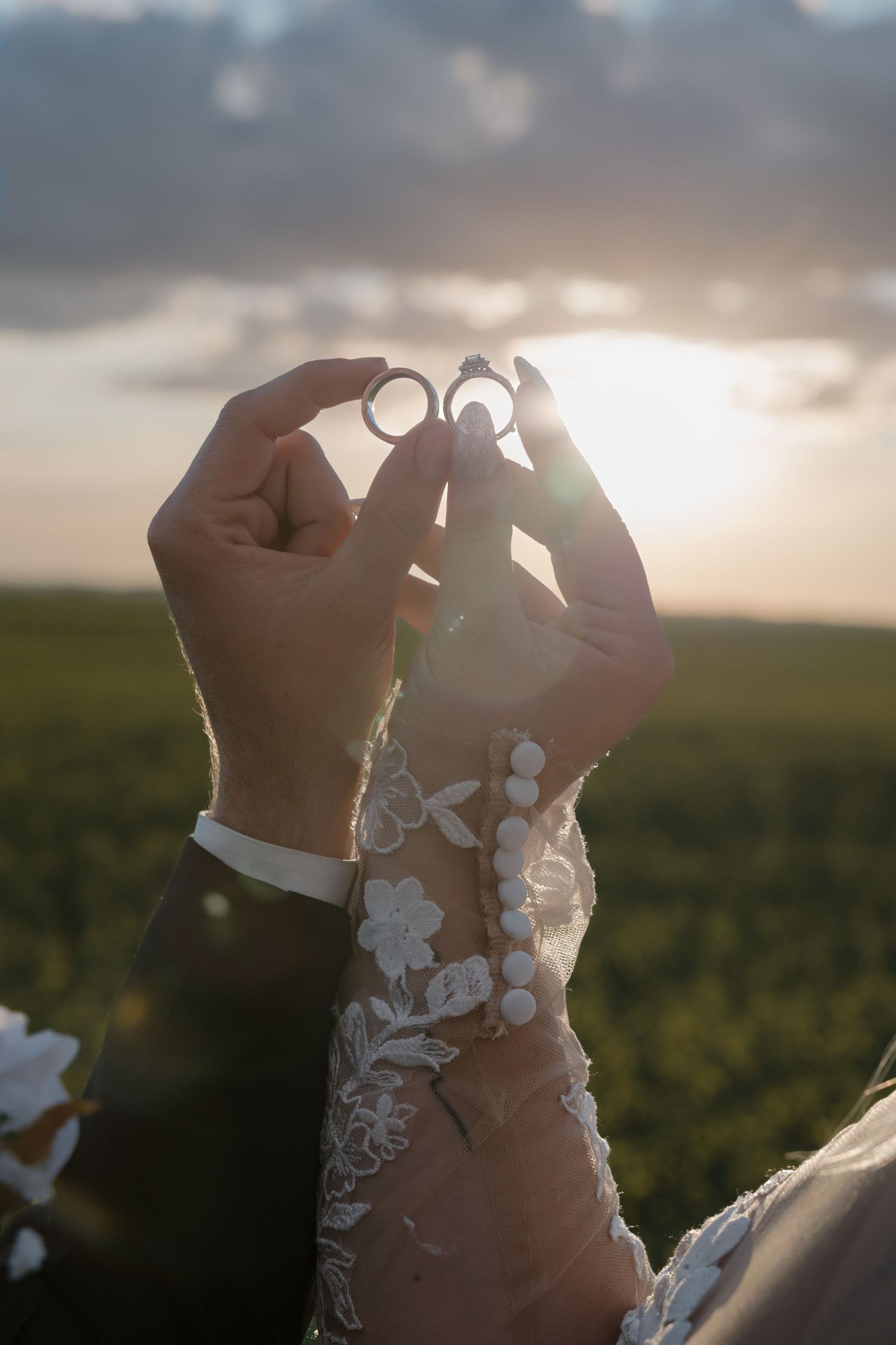 Married couple holding up wedding rings during golden hour in Garrison North Dakota wedding photography