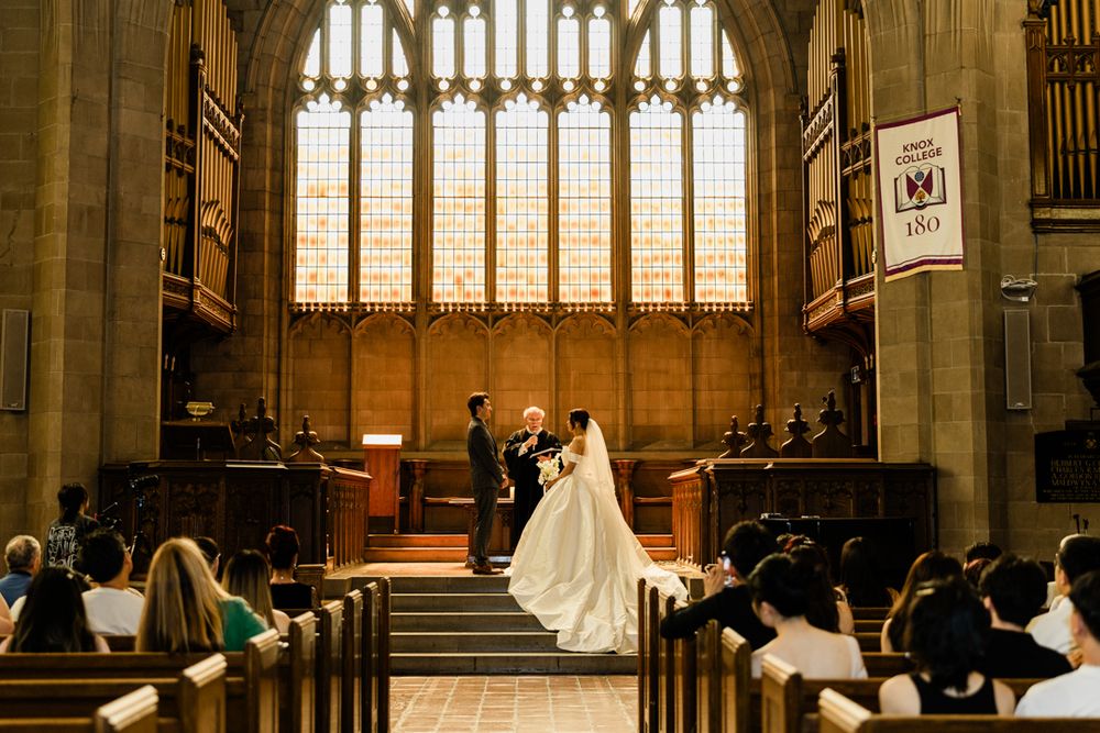 Bride and groom stand before officiant at altar during ceremony in Knox Chapel at Knox College.