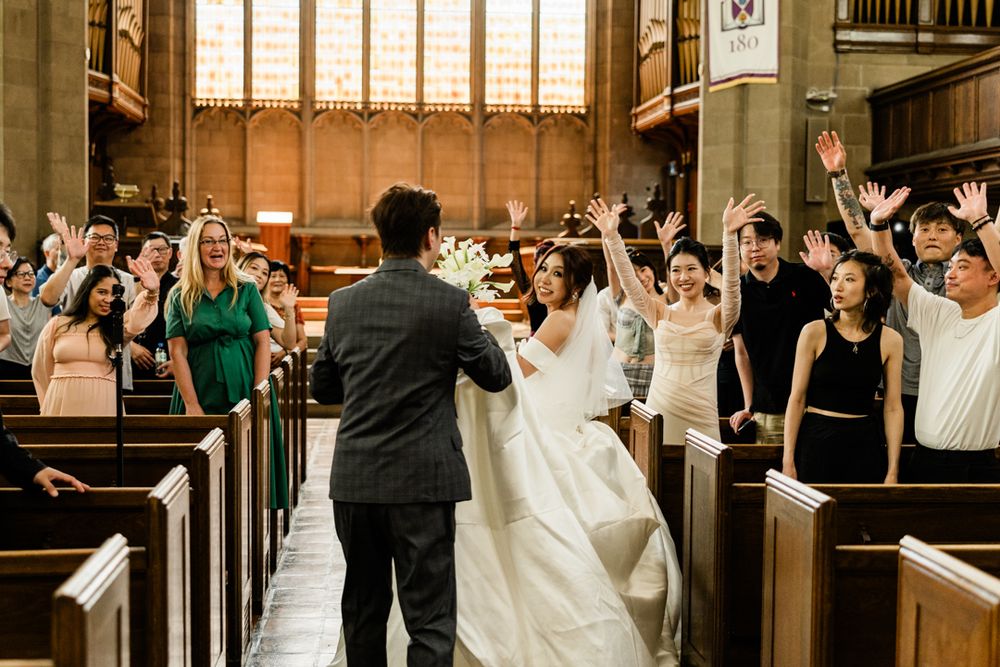 Guests cheer as bride and groom walk down Knox Chapel aisle after Knox College wedding ceremony.
