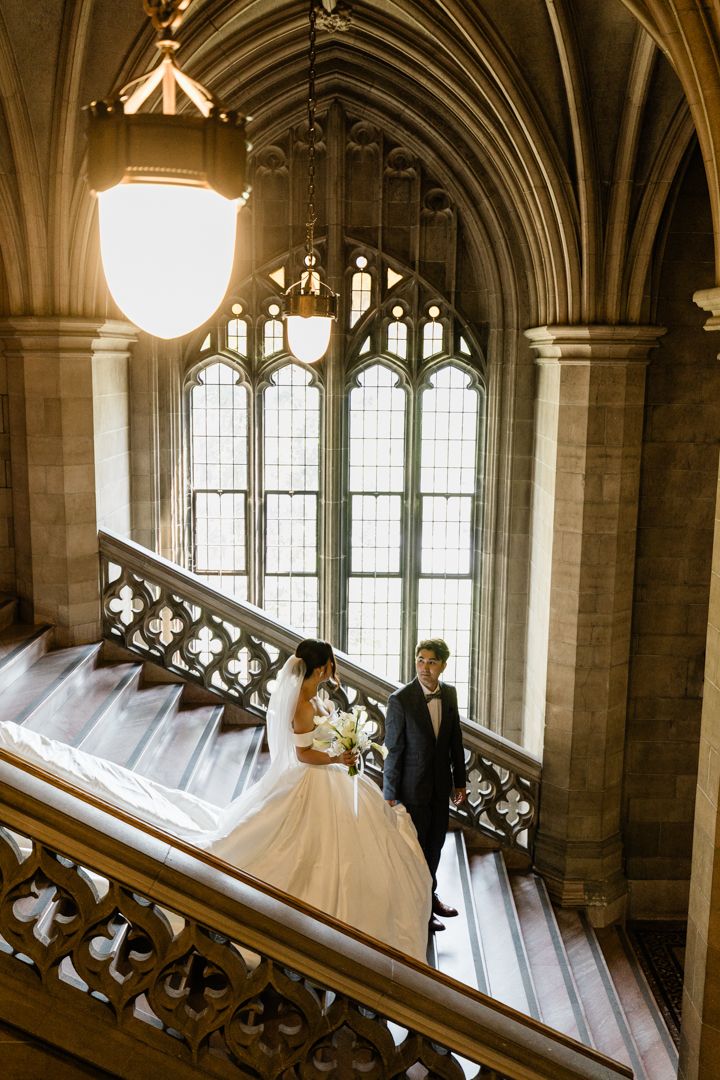 Couple on ornate staircase with stained glass windows during Knox College wedding photo shoot.