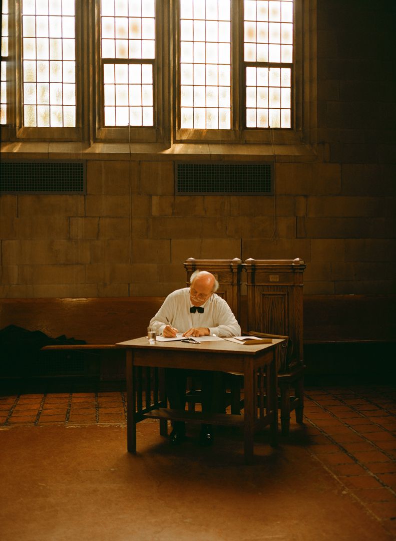Wedding officiant writing at a wooden desk inside Knox Chapel during a Knox College wedding.