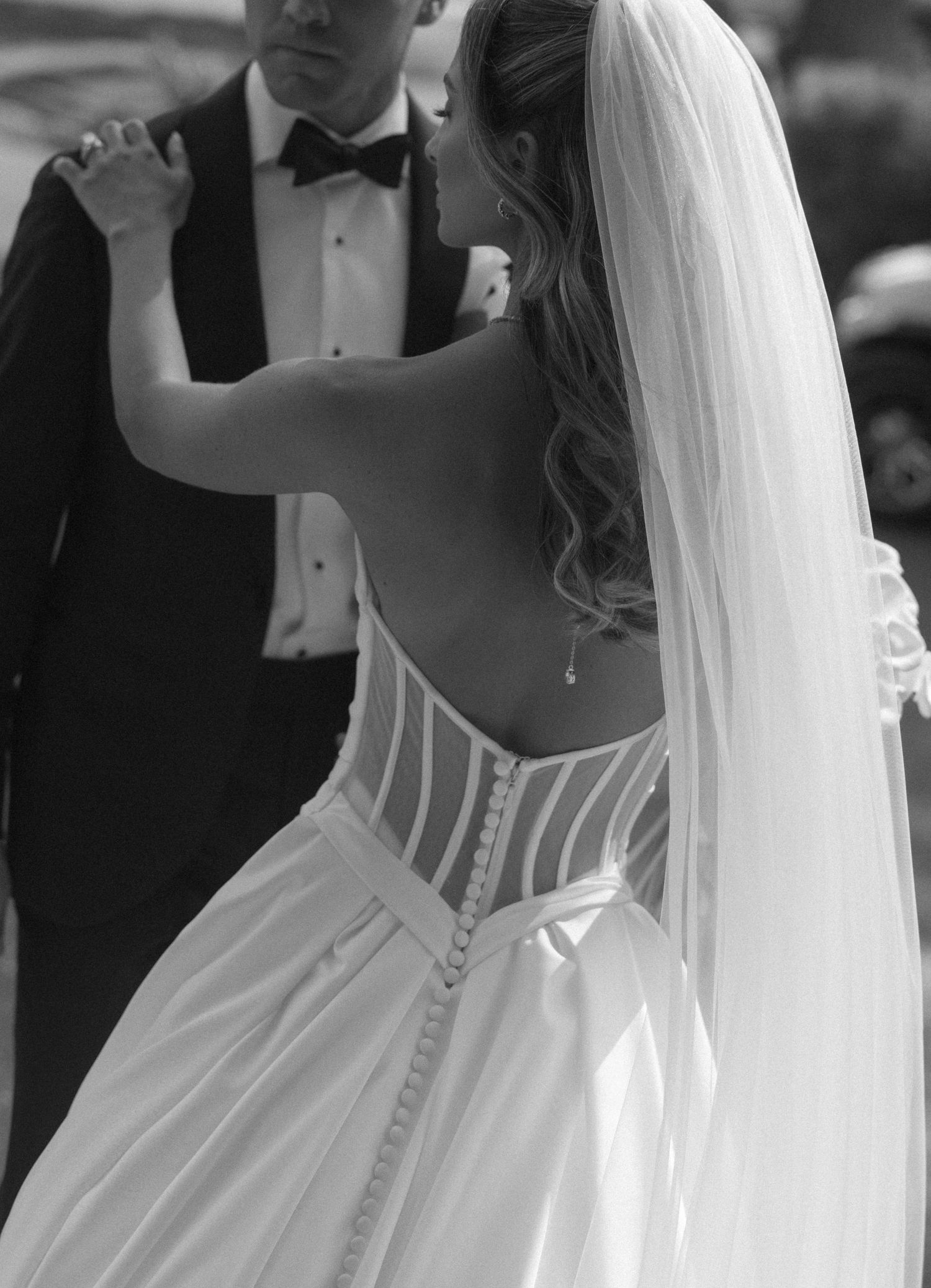 Close-up black and white photo of bride in backless corset wedding gown with veil.