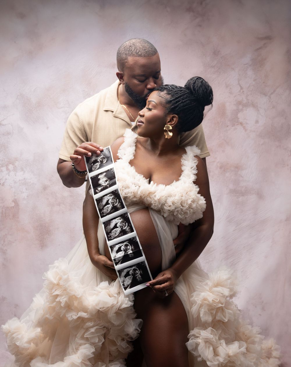 A couple holds an ultrasound photo while embracing in a romantic maternity photoshoot.
