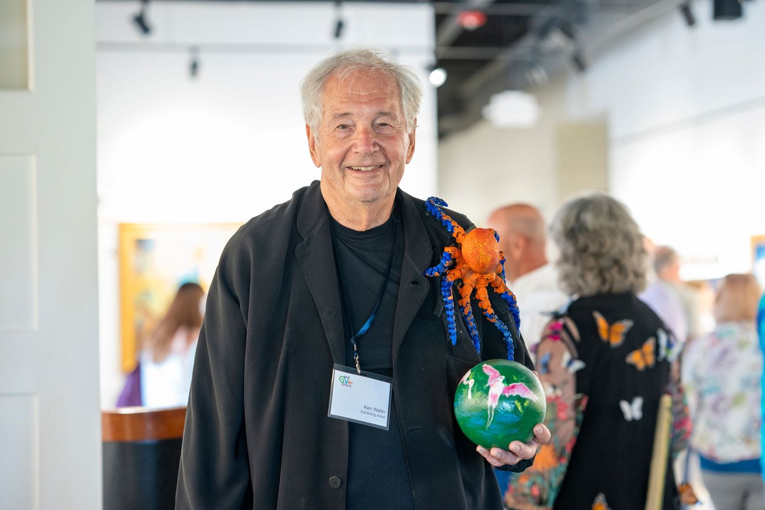 A person holds colorful bowling balls at an indoor event venue.