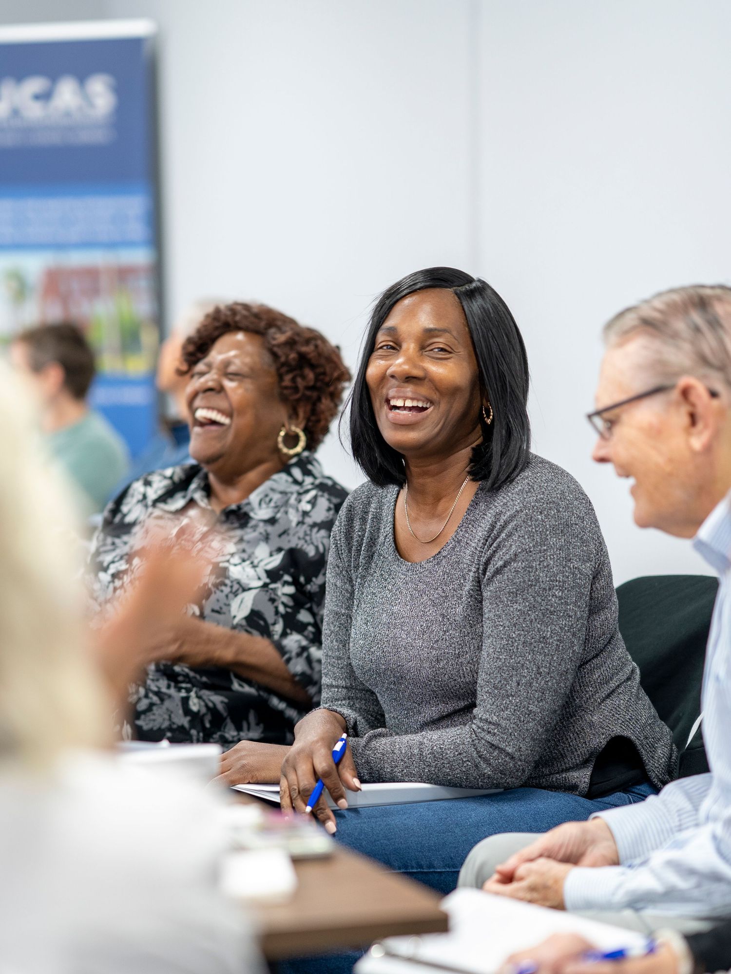 People sit together at a conference table, engaged in animated discussion and laughter.