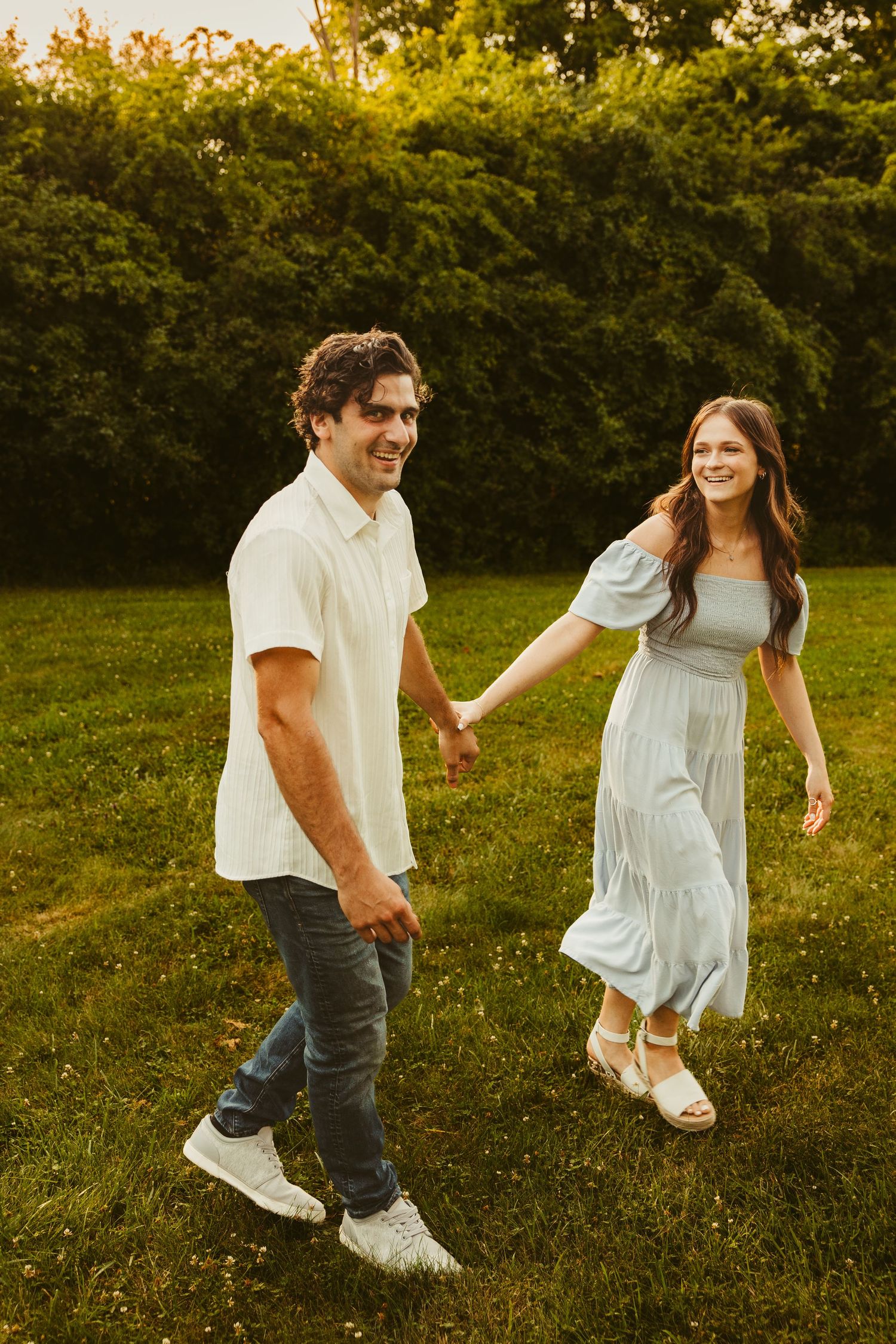 Couple holds hands walking through a park in Livonia, Michigan