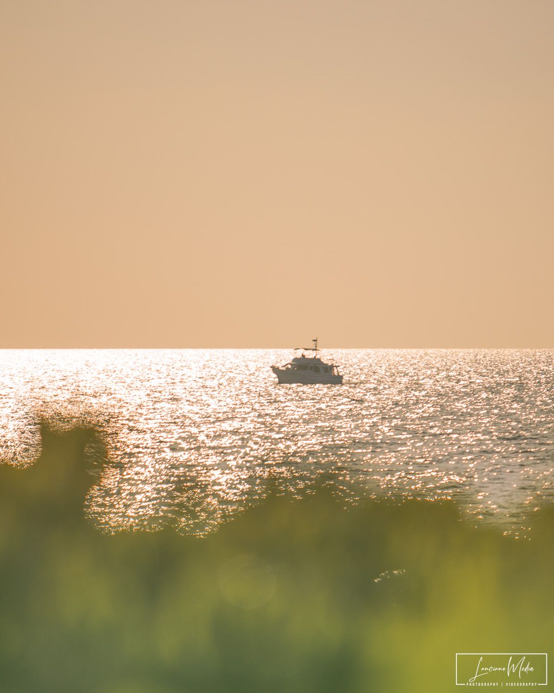 Silhouette of boat on sparkling ocean during golden hour.