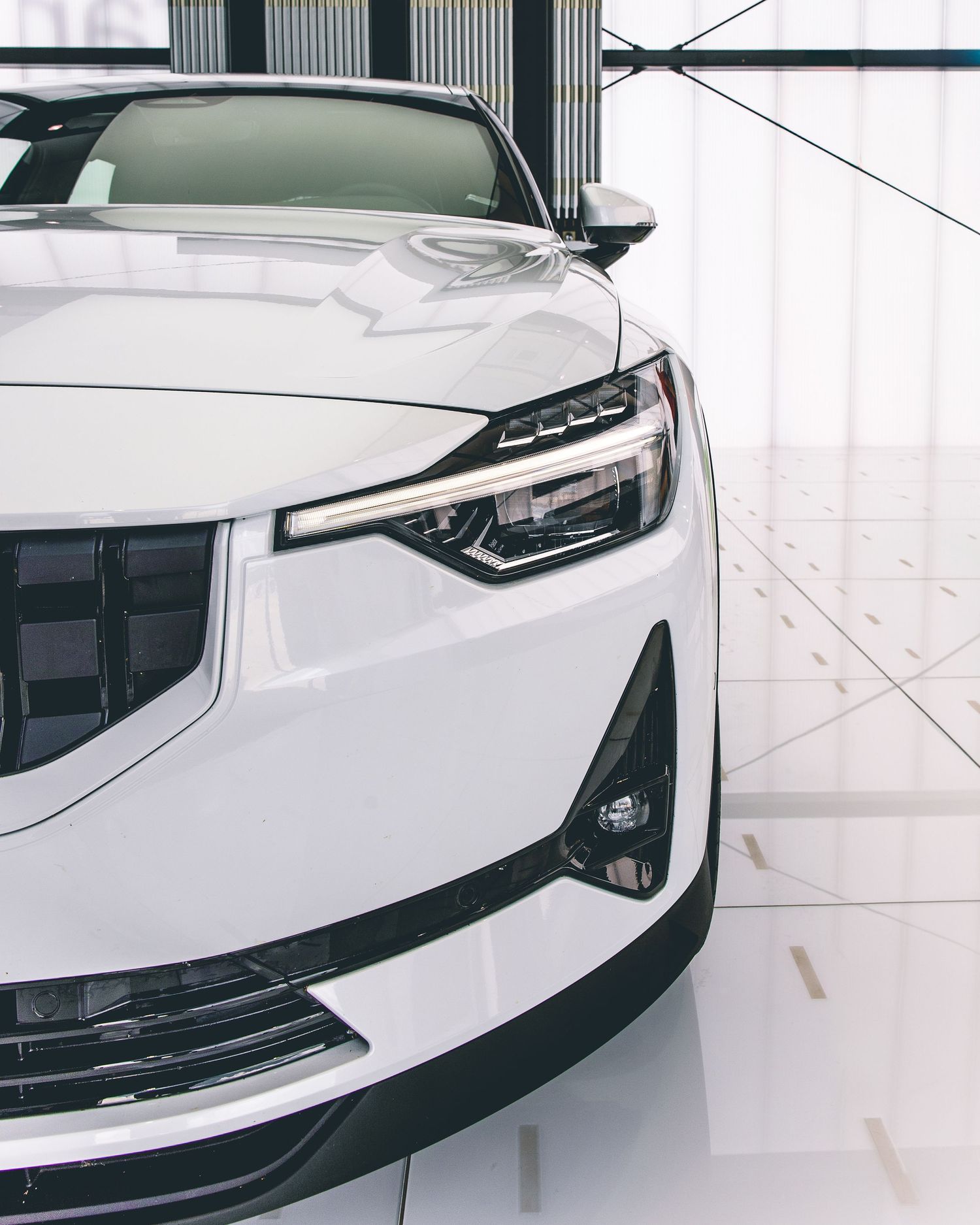 Close-up of white luxury car headlight and front grille design.