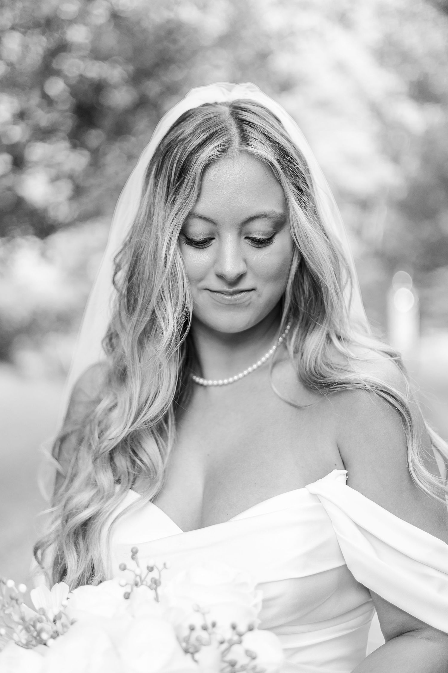 Classic black and white bridal portraits showcase elegant pearl necklace and off-shoulder gown.