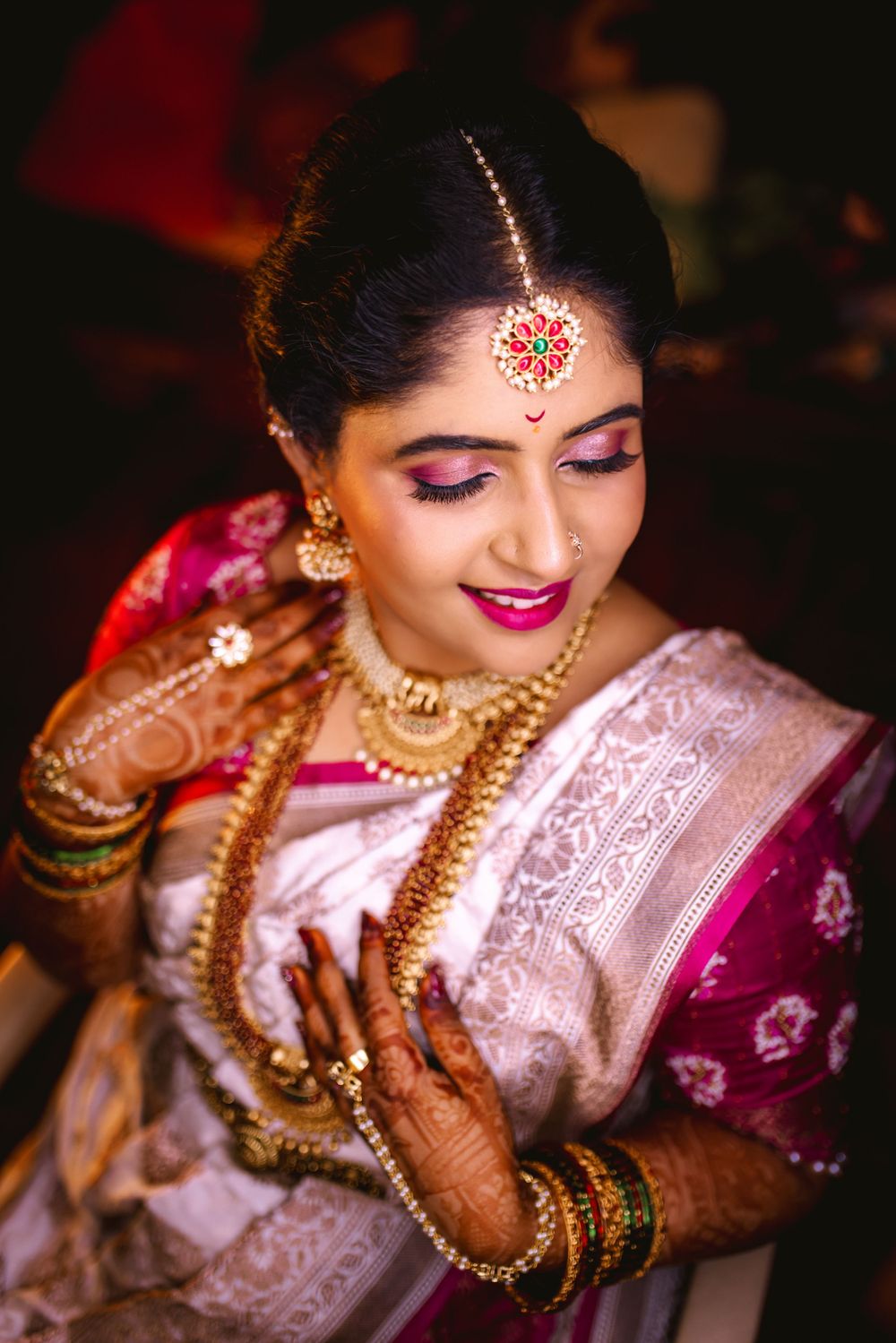 Close-up of traditional Indian bridal jewelry and makeup in warm lighting.