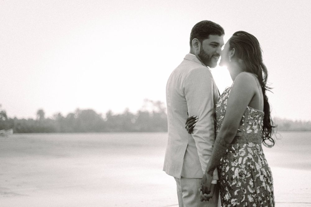 Black and white portrait of couple in formal wear standing against scenic background.