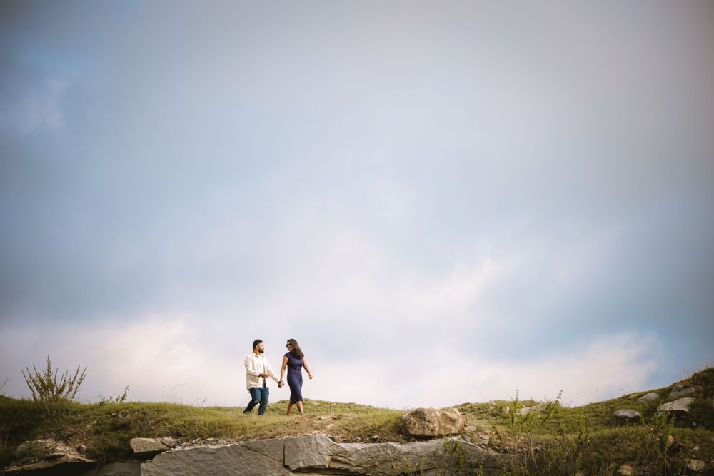 Couple walking together on a grassy hillside path during golden hour.