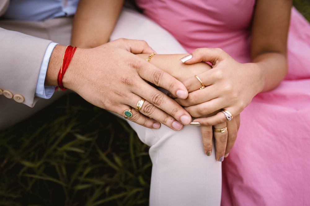Close-up details of hands with rings and pink formal attire.