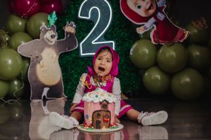 Second birthday party scene with cartoon character decorations and festive cake.