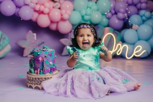 Purple and teal birthday celebration with sparkly cake and 'one' neon sign.