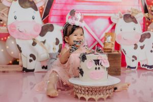 Pink cow-themed birthday party setup with matching cake and decorations.