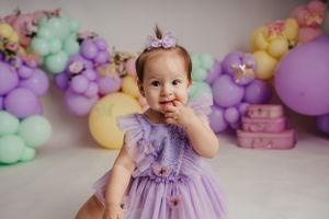 Dreamy birthday setup with pastel balloon garland and purple tulle dress.