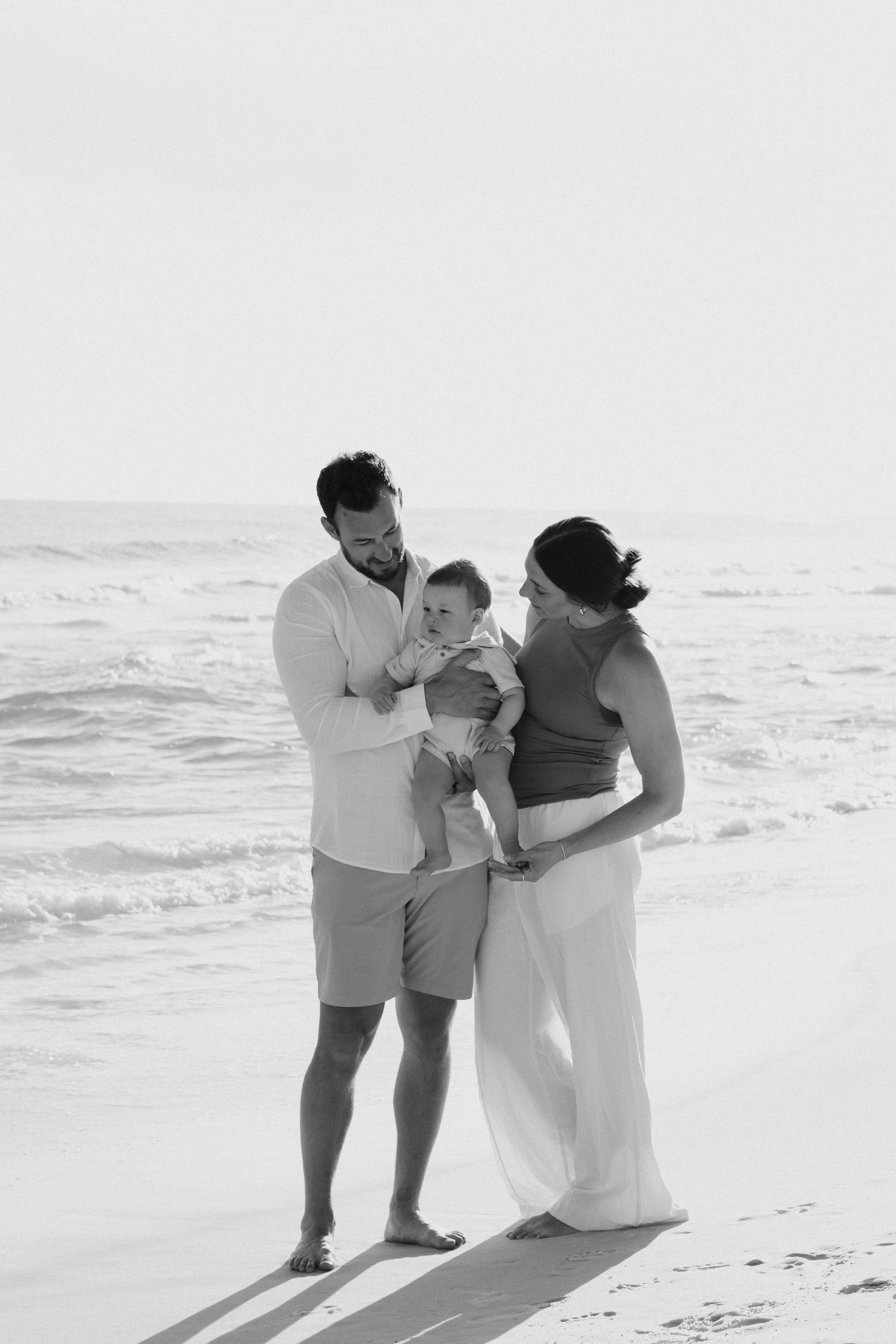 Black and white photo of family sharing tender moment on beach.