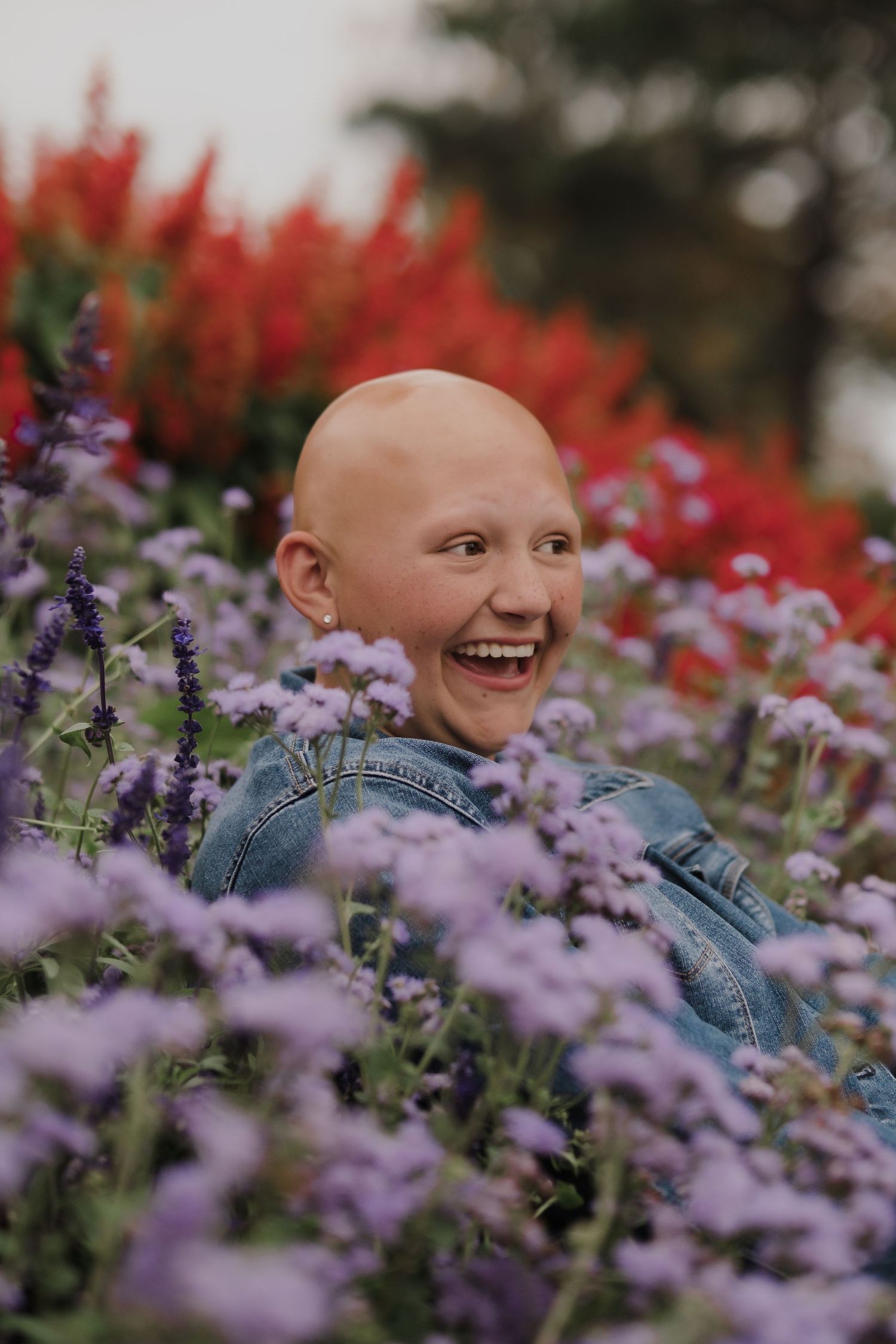 Person lying among purple and red flowers in a garden setting.