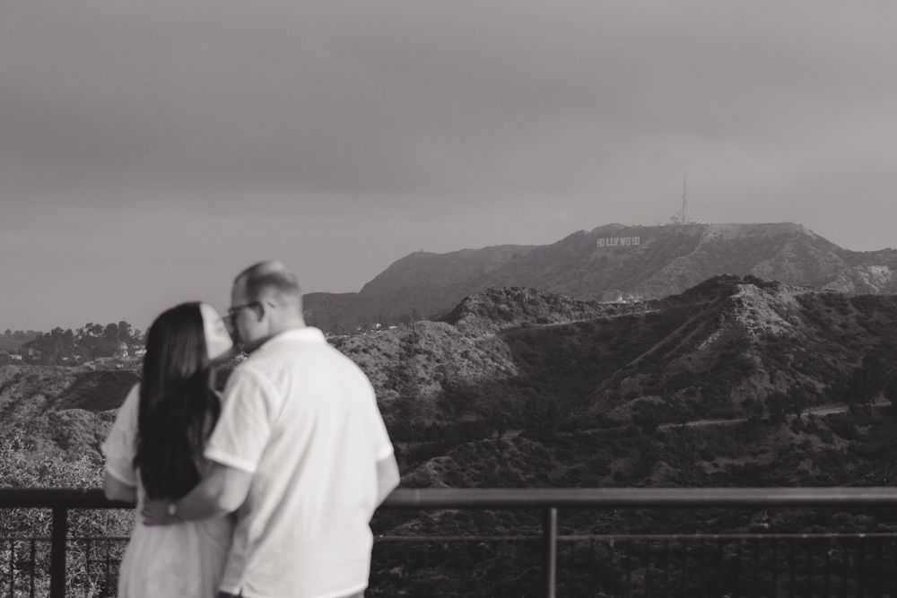 A couple embraces while viewing the Hollywood Sign from an observation point.
