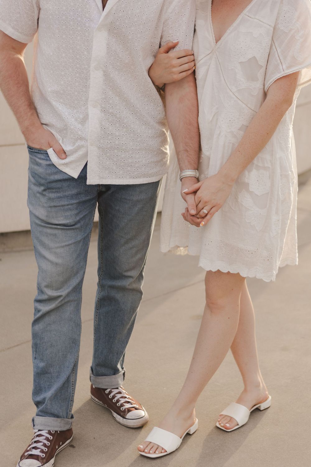 Close-up of a couple's casual outfits showing jeans, white clothing and summer footwear.