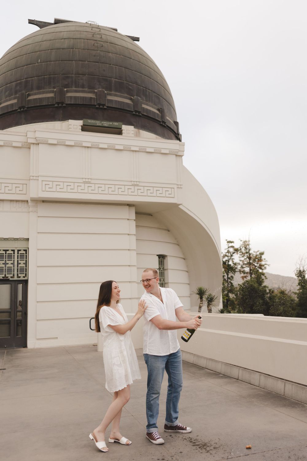 A couple poses together outside the iconic Griffith Observatory dome in Los Angeles.