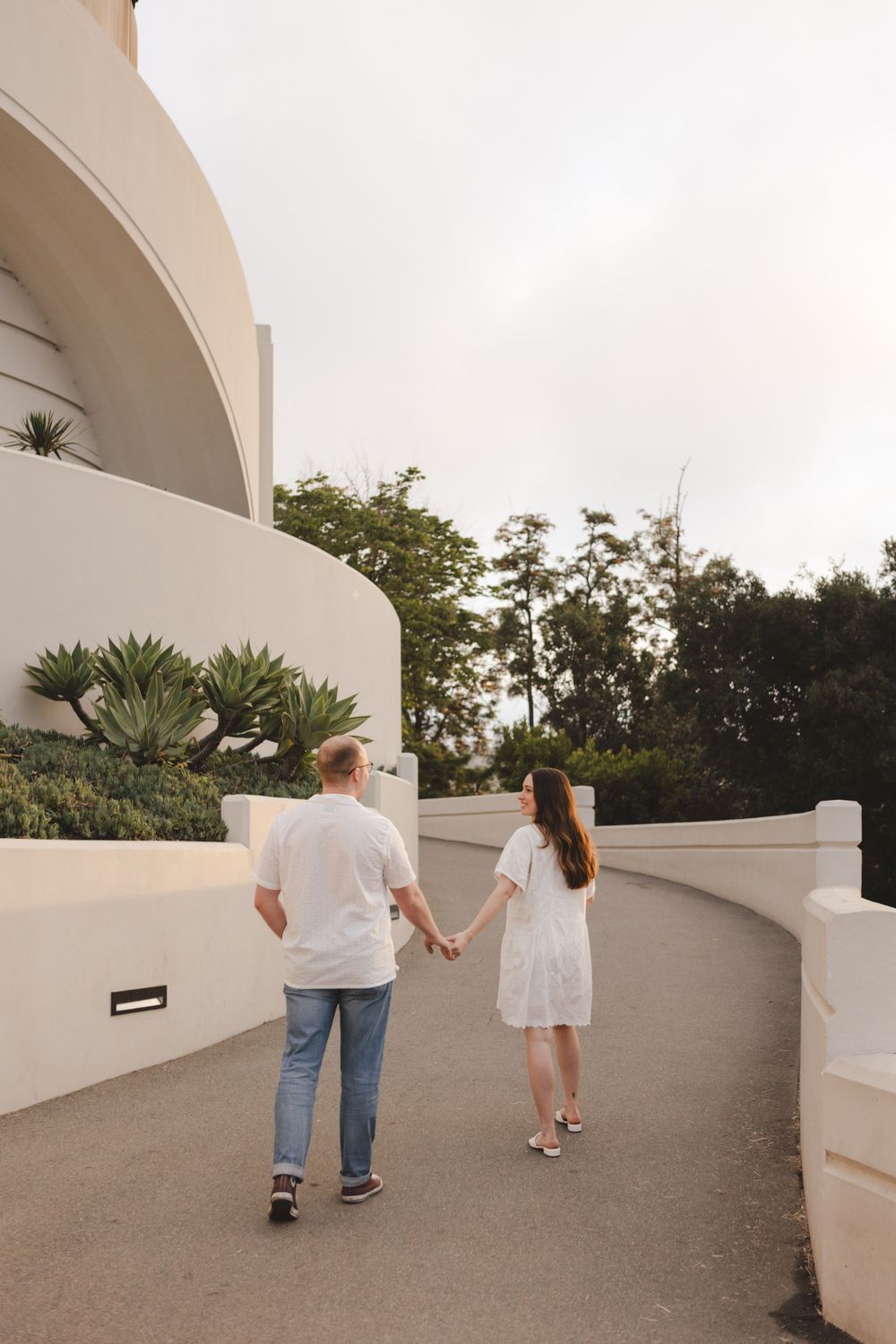 A couple walking hand in hand along the curved path at Griffith Observatory.