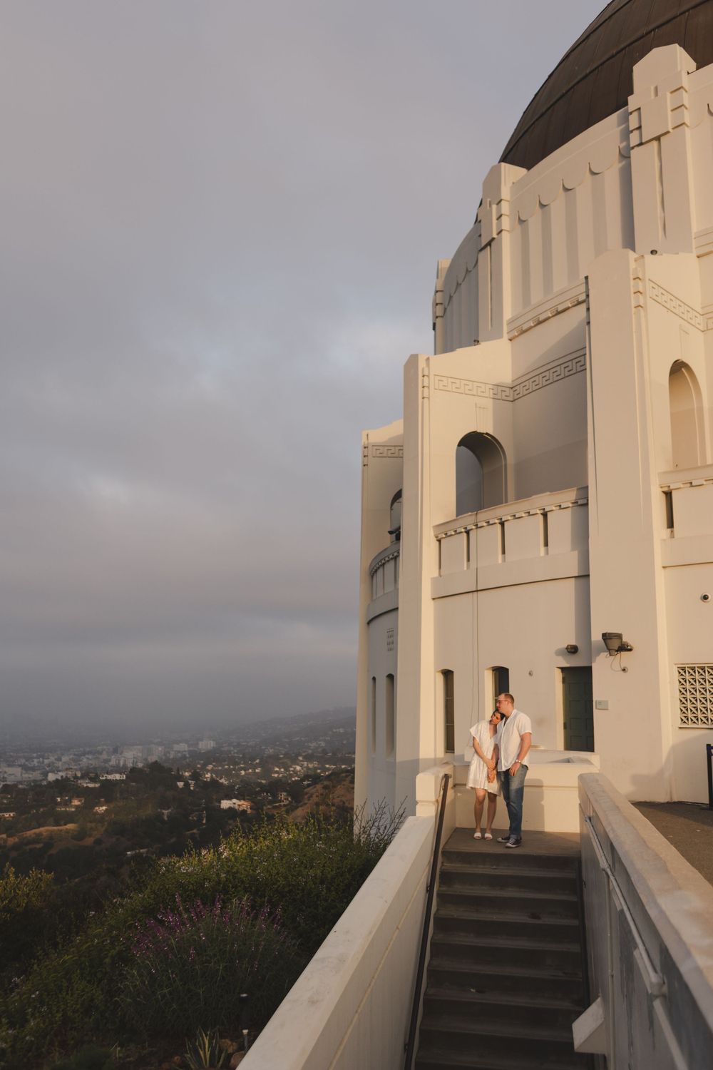 Art deco architecture of Griffith Observatory with city views in background during sunset.