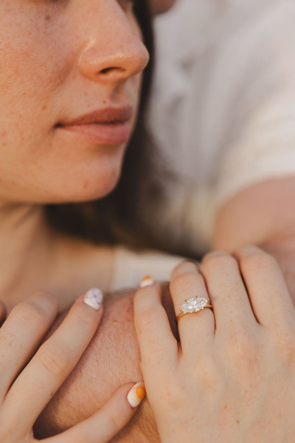Close-up of an engagement ring on a woman's hand with French manicured nails.