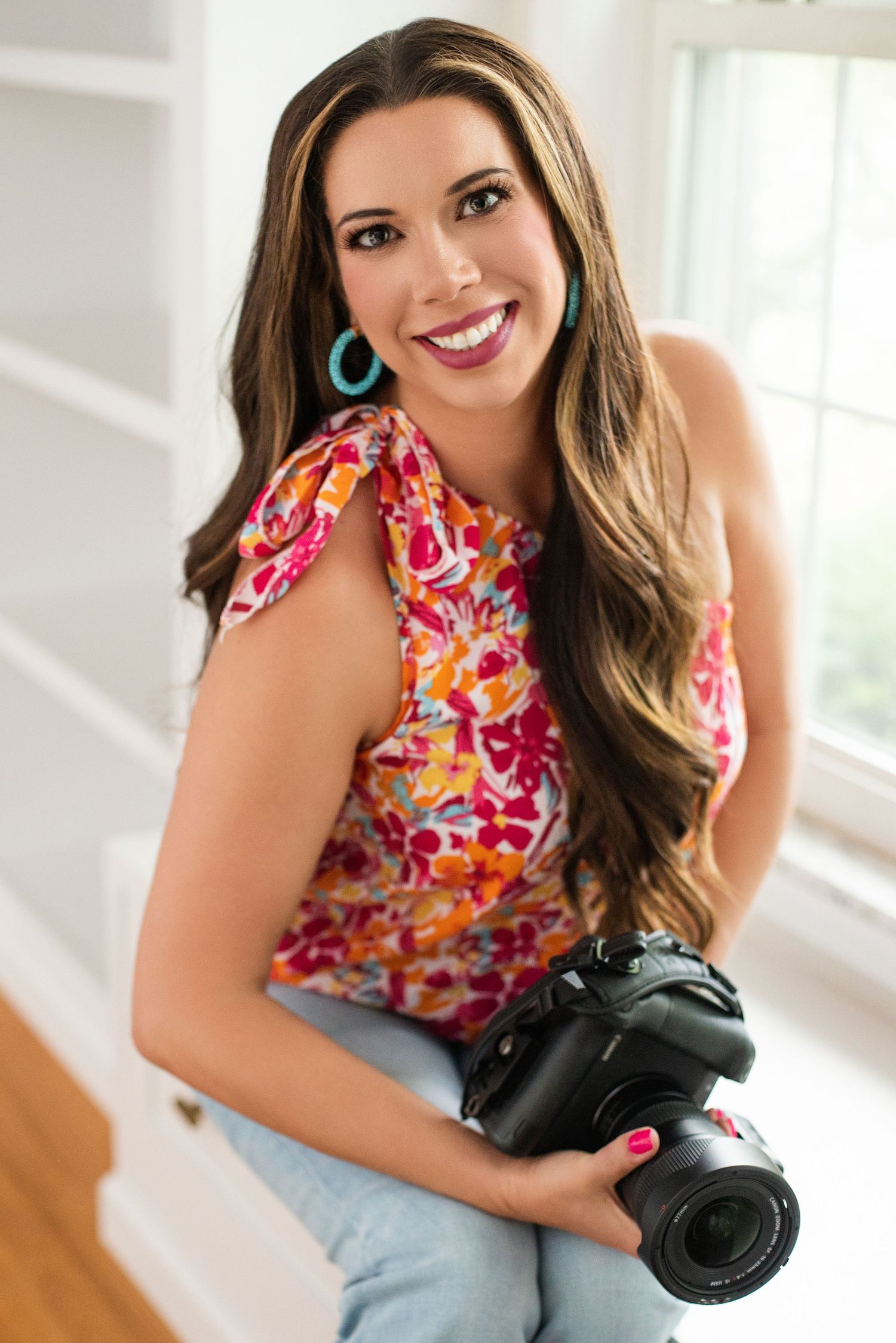 Portrait of photographer in floral top holding professional camera.