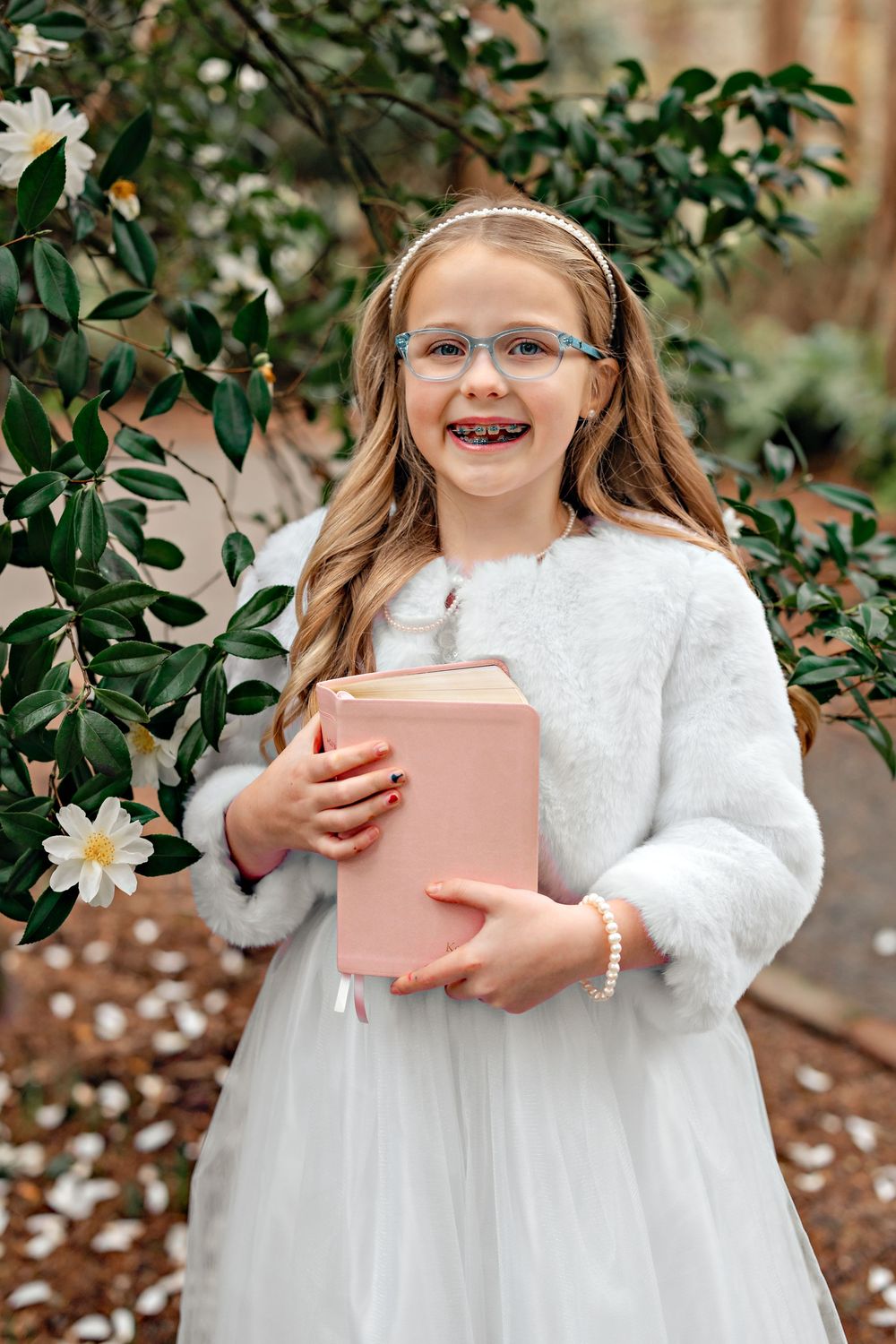 A series of photos showing someone in a white lace dress holding a pink book against a green garden background.