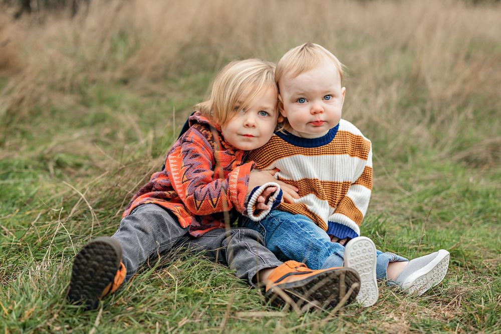Two people laying in tall brown grass on a sunny autumn day enjoying the outdoors together.