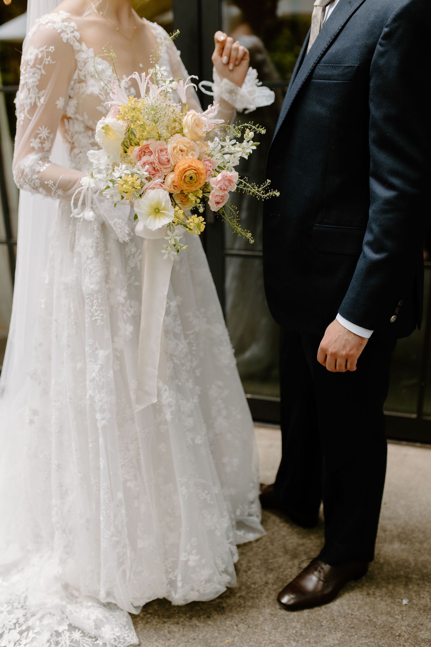 Elegant wedding attire details with lace gown and pastel floral bouquet.