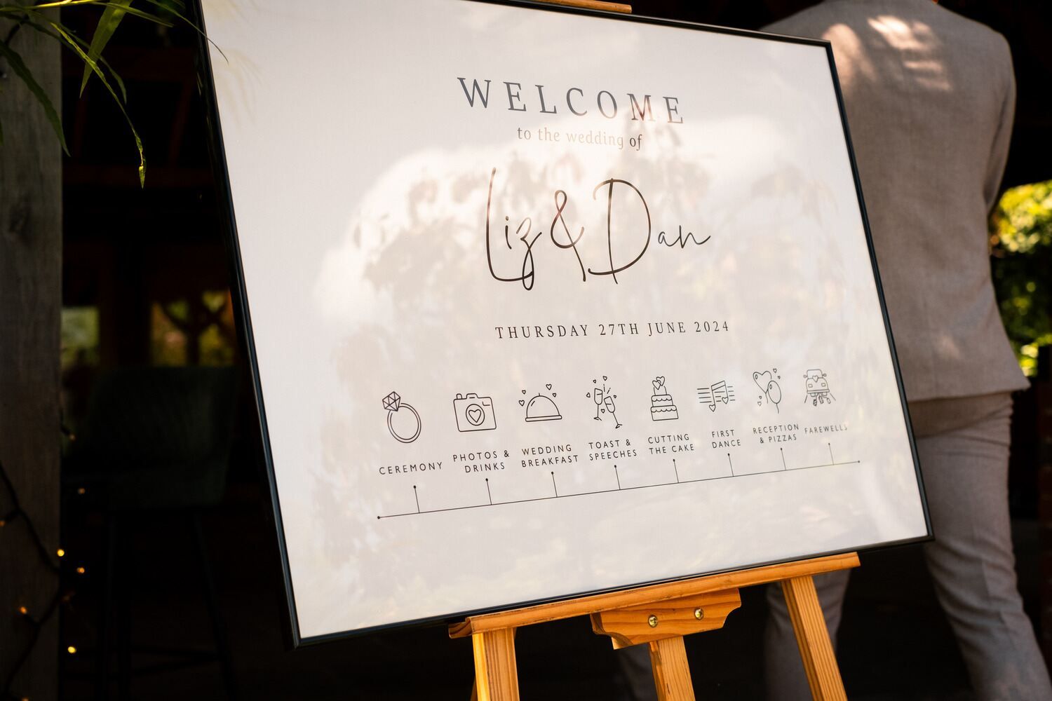 Wedding sign on an easel with a timeline for the day, reading: "Welcome to the wedding of Liz & Dan etc