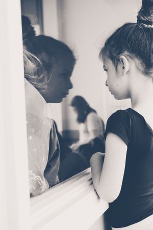A black and white artistic photo showing reflection of figures in profile against a light background.