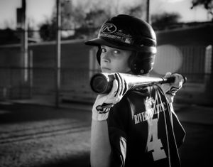Black and white photo of a young baseball player in uniform number 4 holding a bat at the ready position.