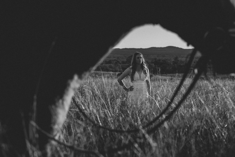 A dreamy black and white photo taken through grass of someone walking in a field.
