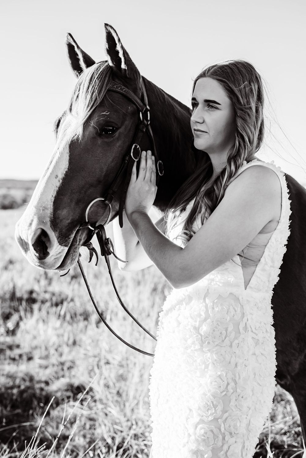 Close-up black and white portraits with a horse and white lace dress in a field setting.