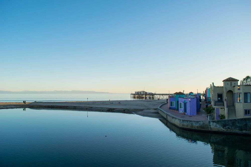 Tranquil waterfront view with a pier and colorful buildings at sunset.