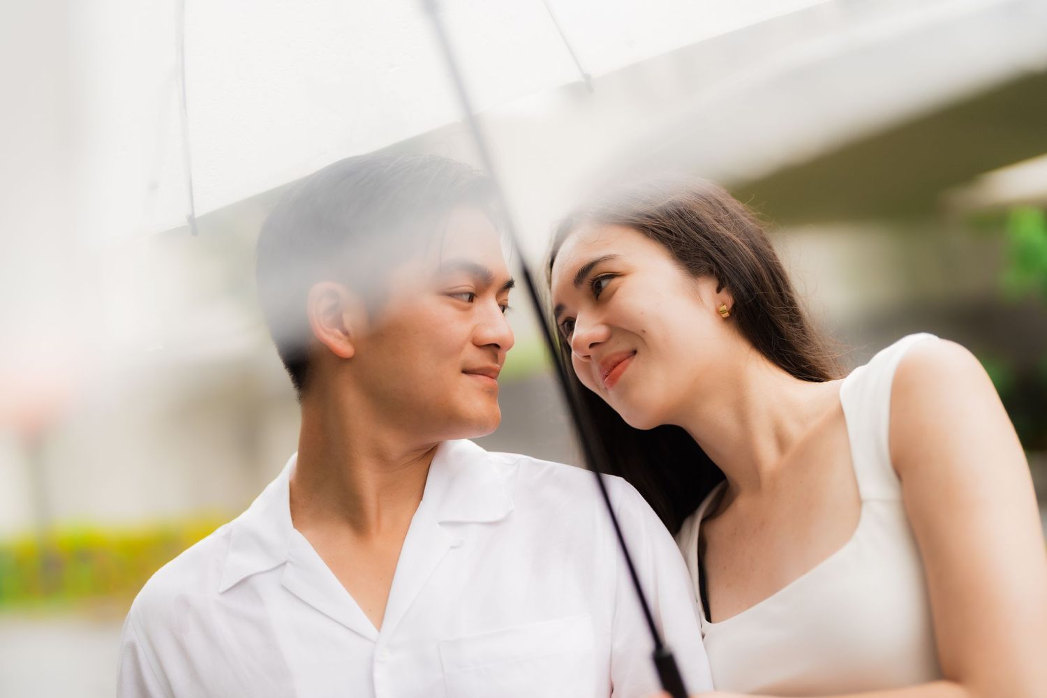 Intimate close-up of couple sharing tender moment under white umbrella.