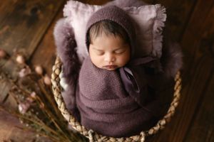 An Indian newborn wearing a deep purple wrapped in a basket. - Greenville SC newborn photographer - Easley SC newborn photographer