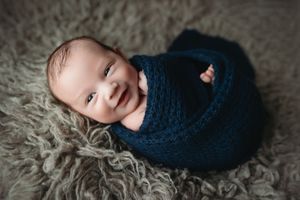 A smiling newborn boy in navy blue on grey rug. Greenville SC newborn photographer. - Easley Sc newborn photographer. Greenville SC photos
