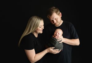Mom and Dad are holding the newborn, and the newborn boy is smiling. Greenville SC newborn photographer. - Easley Sc newborn photographer. G