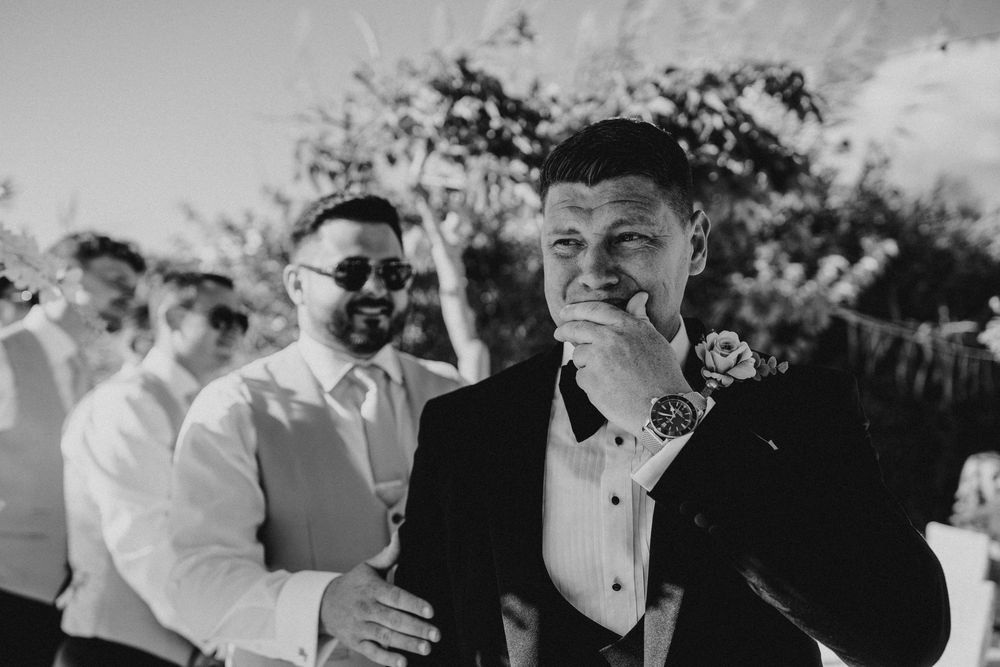 A black and white photo capturing joyful moments at an outdoor wedding celebration.