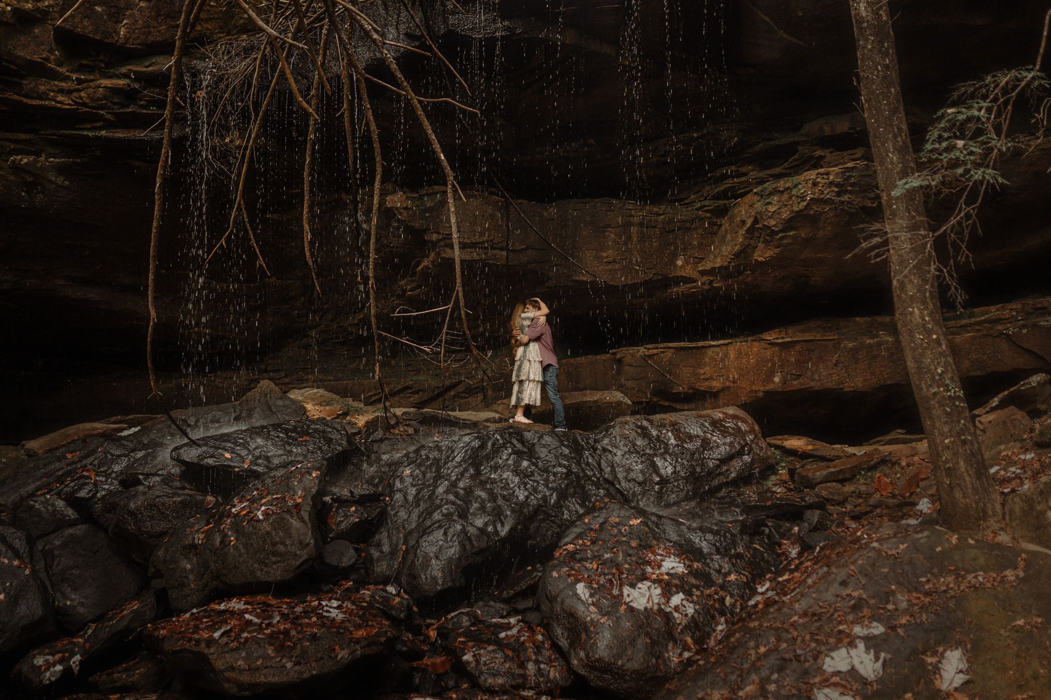 A dramatic portrait on rocky terrain with a cave formation in the background.