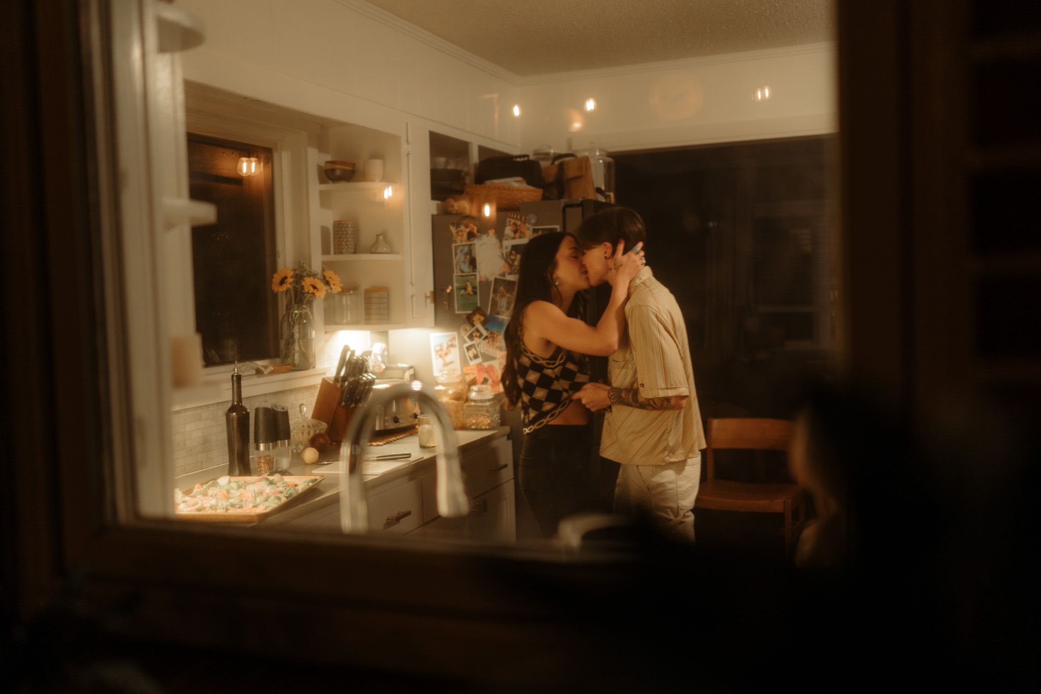 A cozy intimate moment in a warmly lit kitchen at night.