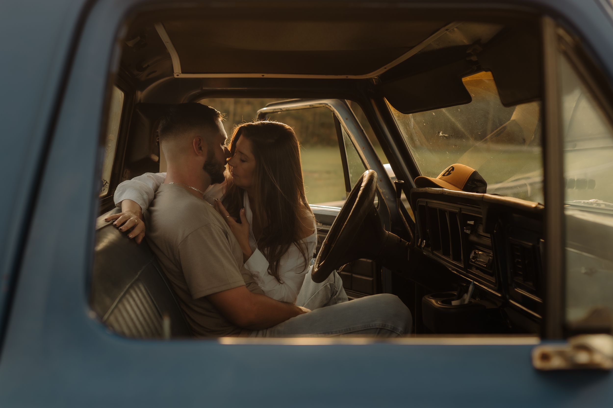 A romantic moment captured through a vintage car window with moody lighting.