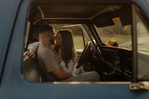 A romantic moment captured through a vintage car window with moody lighting.