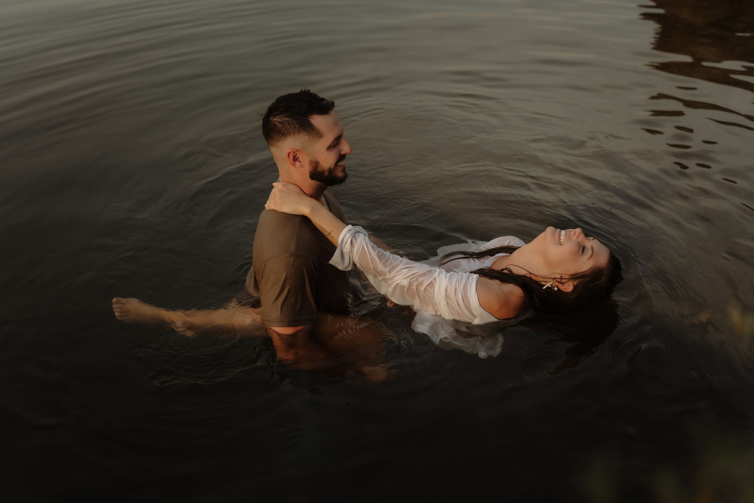 A couple creates a romantic scene while wading in dark water.